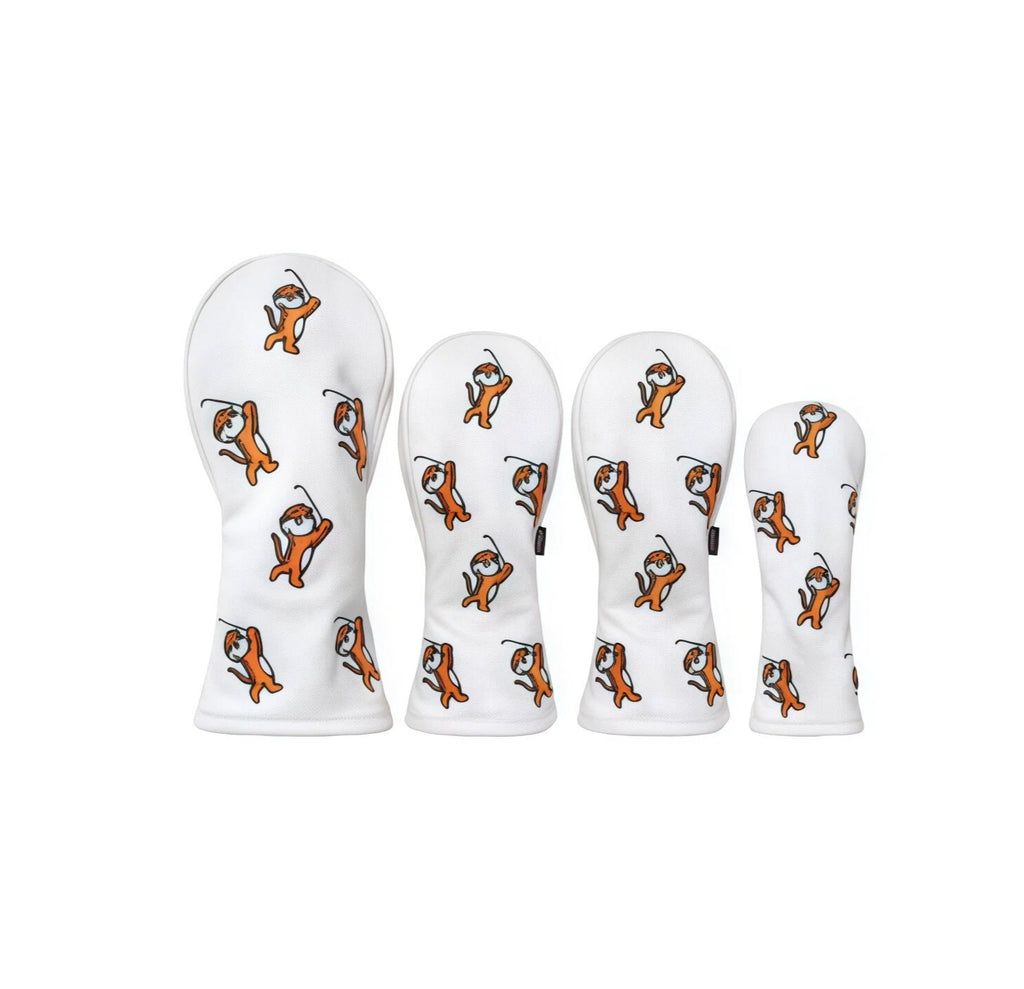 Close-up of a four-piece white golf headcover set with repeating orange cartoon tigers swinging golf clubs, perfect for protecting driver, fairway, hybrid, and utility clubs with fun style.