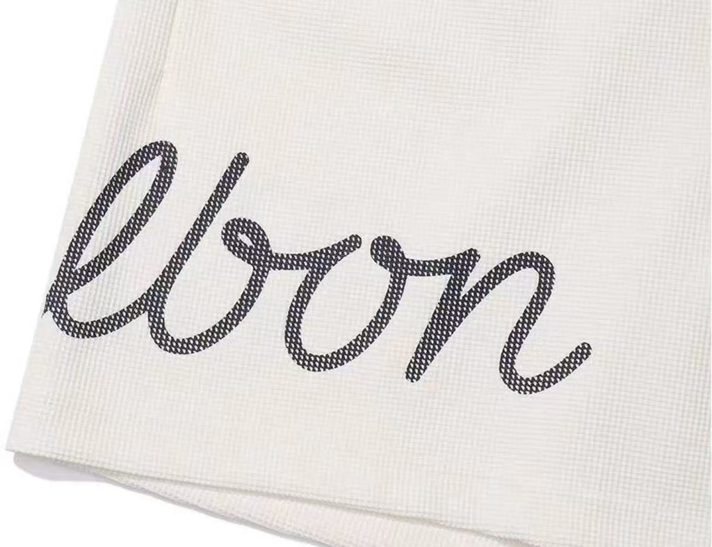 Malbon white golf shorts leg logo close-up