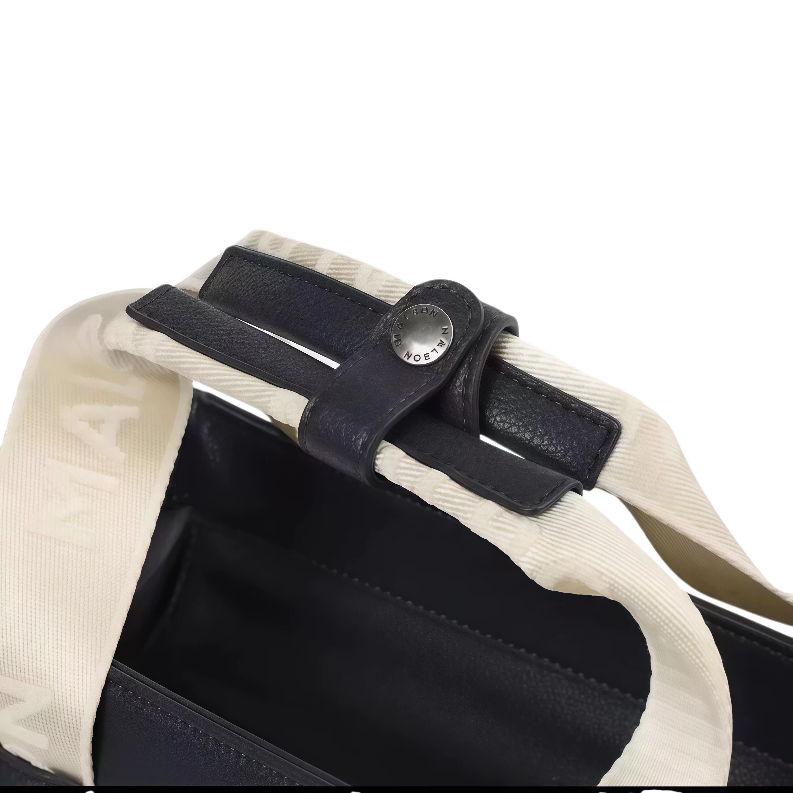 Close-up of black Malbon Golf tote bag handle showing cream MALBON woven webbing strap, leather keeper loop and engraved silver snap stud
