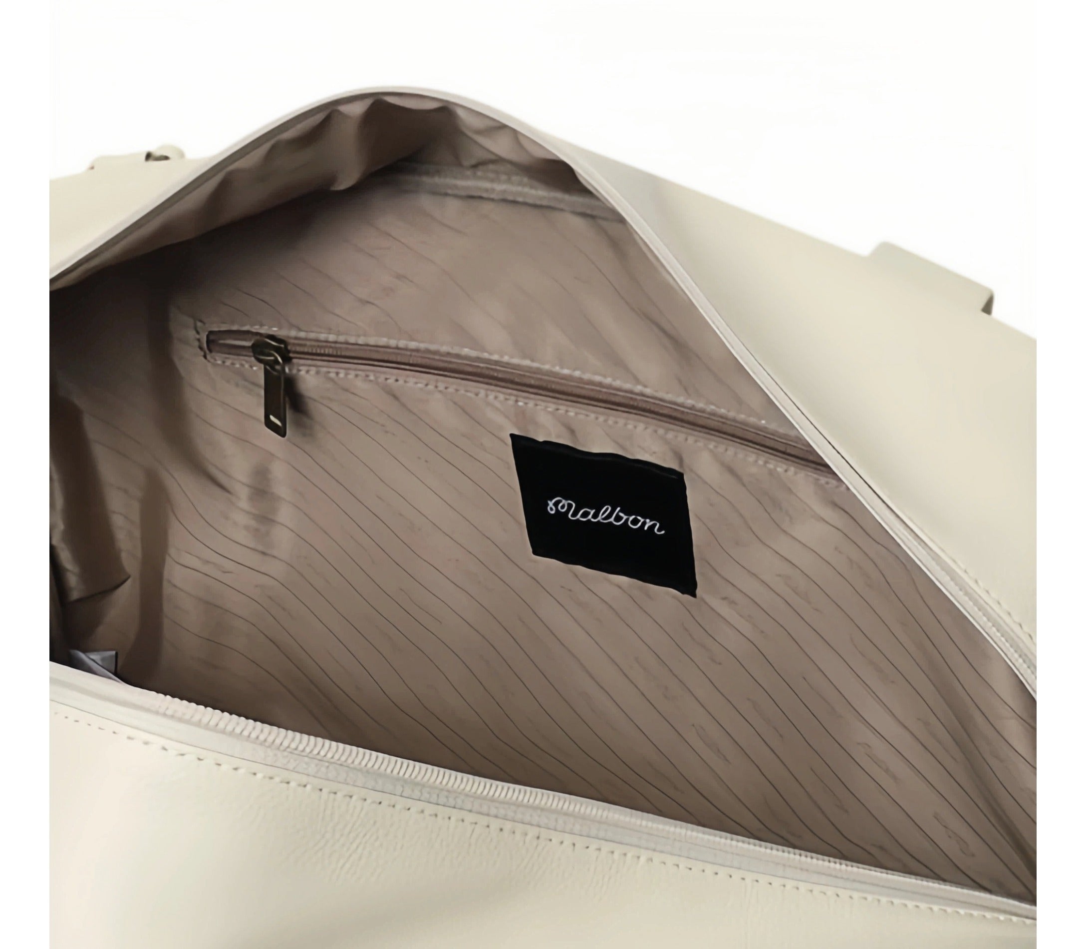 Close-up of Malbon Golf duffel bag interior showing striped lining, zippered inner pocket, and black "Malbon" brand tag for organization and branding