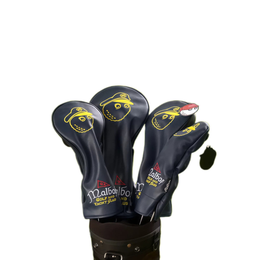 Malbon golf headcovers featuring yellow cartoon captain face logo and “Malbon Golf and Yacht Club” text, fitted on driver and fairway woods in a black golf bag.