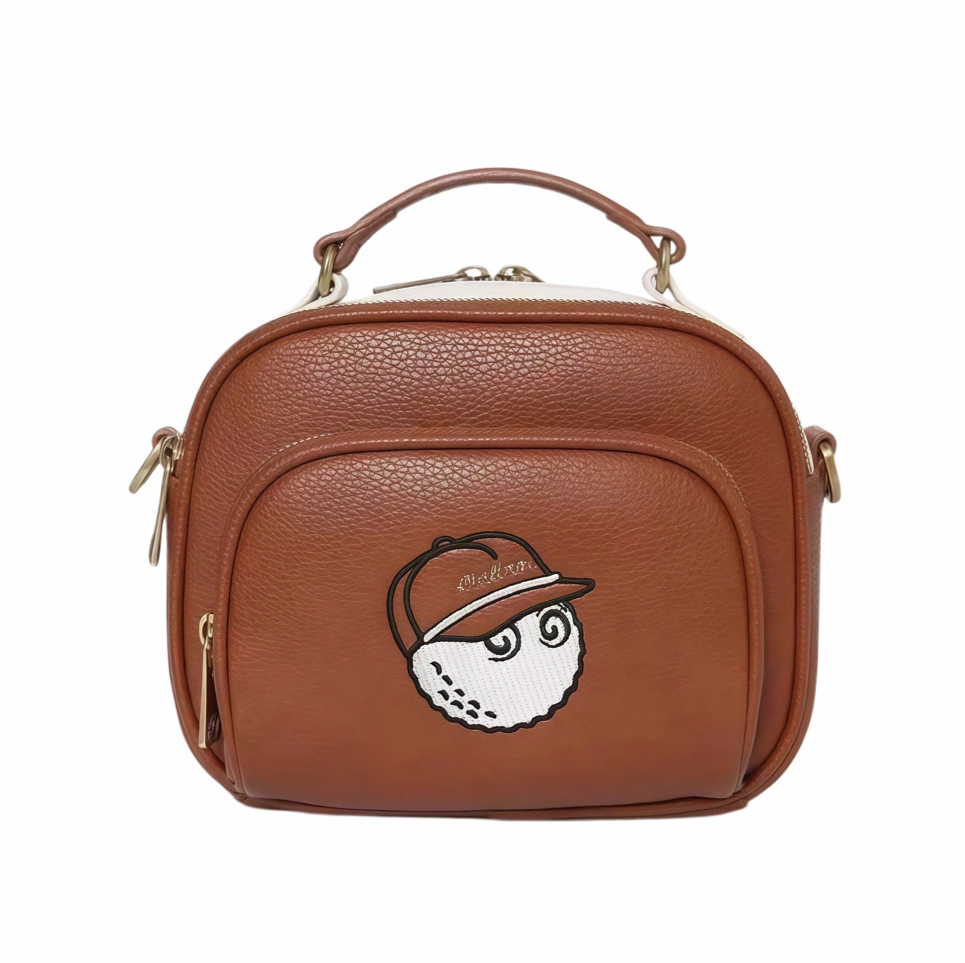 Front view of Malbon Golf Heritage Boston bag in tan brown PU leather featuring embroidered golf ball mascot wearing cap with "Malbon" text, top handle, gold-tone zippers, and structured design
