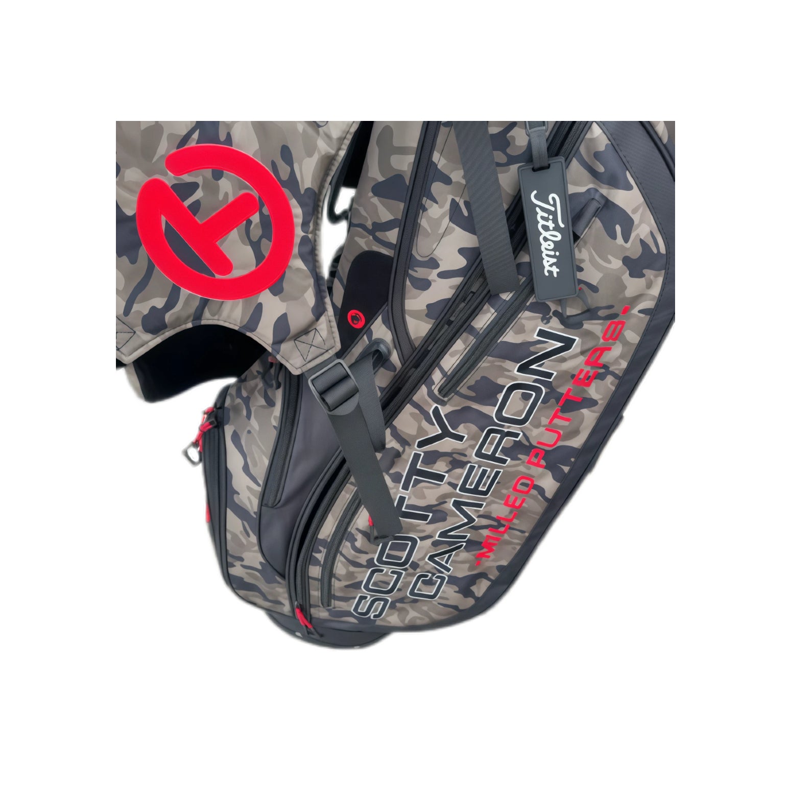 Close-up of the Scotty Cameron Junior Camo-Red Stand Bag, focusing on the vibrant red Circle T logo, "SCOTTY CAMERON MILLED PUTTERS" text, and Titleist tag on the camouflage fabric.